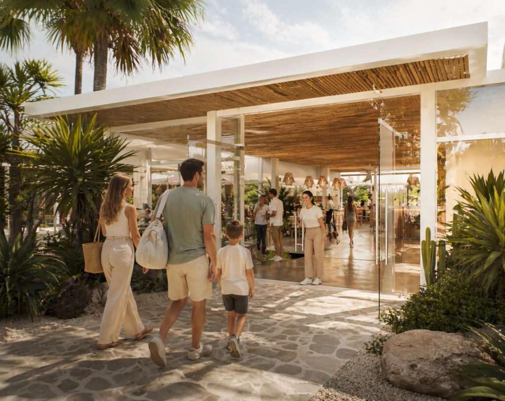 A family walking toward the glass-fronted club entrance on a sunny day